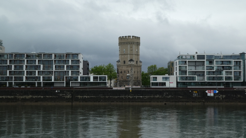 Photo de deux barres d’immeubles modernes encadrant une tour qui semble ancienne, come une tour de chateau fort