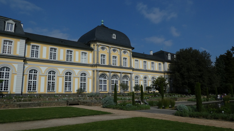 Photo prise au jardin botanique de Bonn: une construction jaune avec un dome devant des allées de jardin bin entretenues